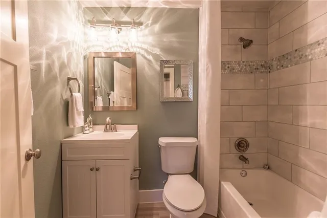 a bathroom with a toilet a sink a mirror a bathtub and shower