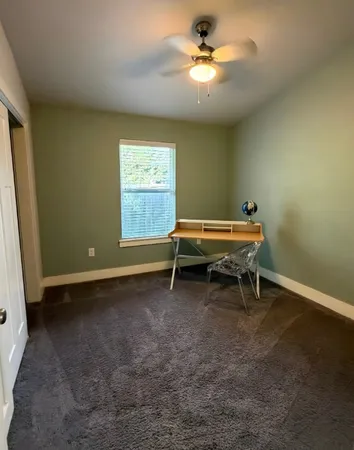a view of a room with windows a ceiling fan and a wooden floor