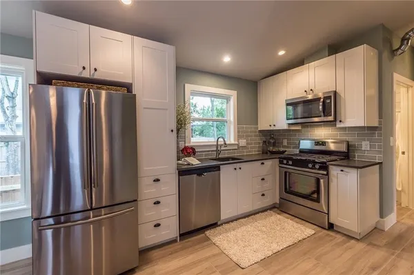 a kitchen with granite countertop a refrigerator stove and microwave