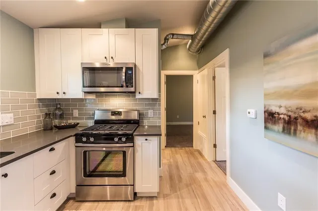 a kitchen with cabinets stainless steel appliances and wooden floor