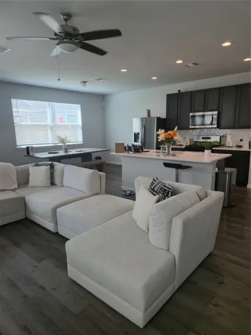 a living room with couches and kitchen view with wooden floor