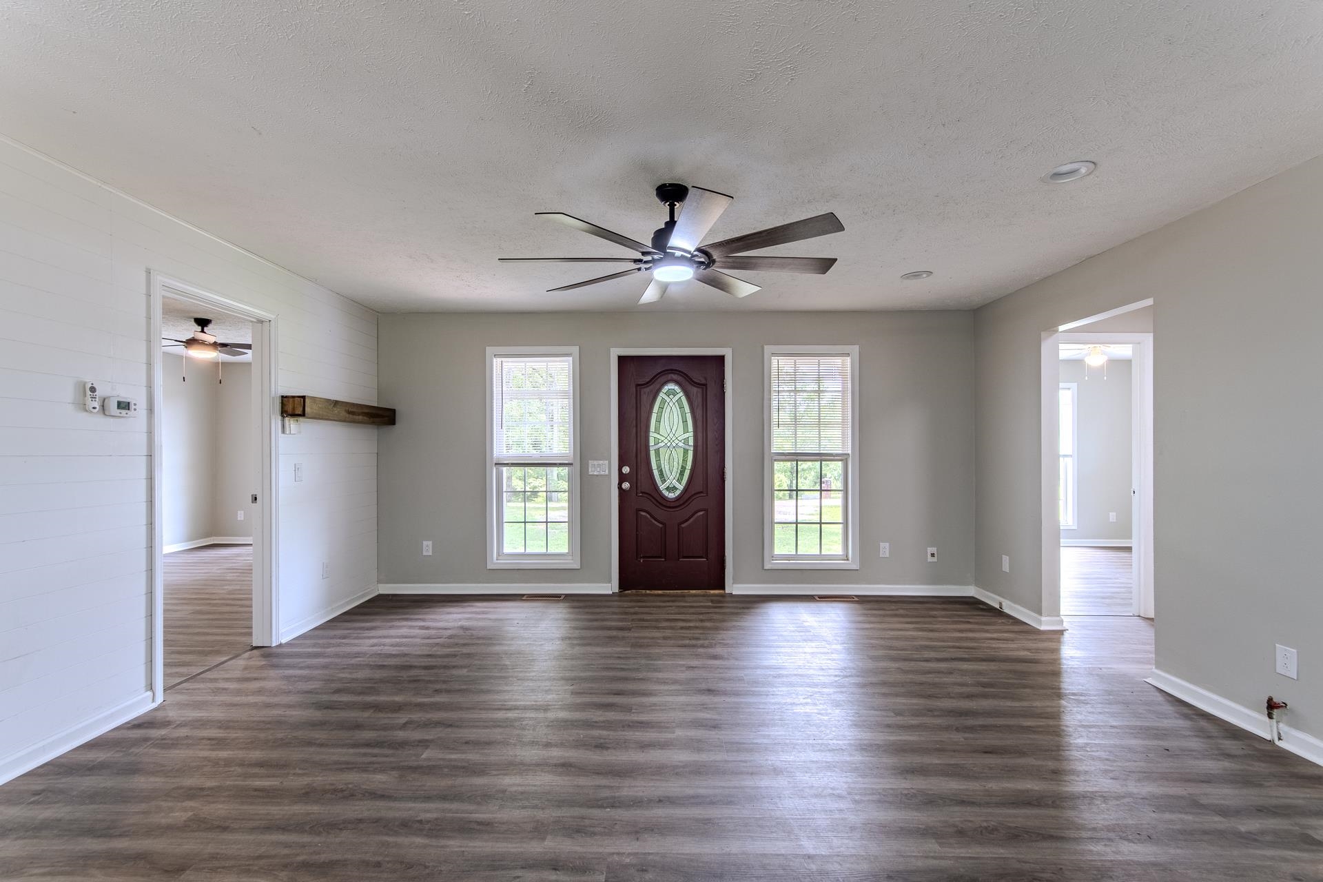 1633 Hardin Graveyard Road Adamsville, TN 38310 - Photo 7 of 33 an empty room with wooden floor a ceiling fan and windows