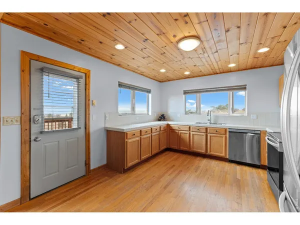 a kitchen with stainless steel appliances kitchen island granite countertop a stove a sink a refrigerator white cabinets and wooden floor