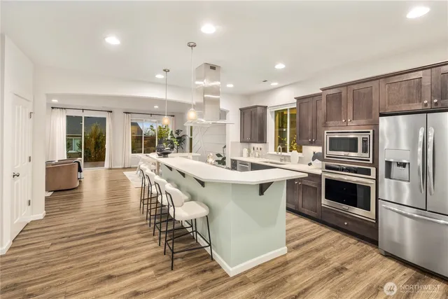 a kitchen with stainless steel appliances a dining table chairs microwave and sink