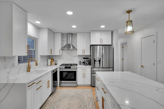 a kitchen with stainless steel appliances granite countertop a sink stove a refrigerator and a refrigerator with wooden floor