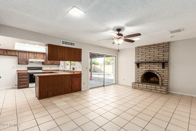 a open kitchen with cabinets a stove a sink and a fireplace