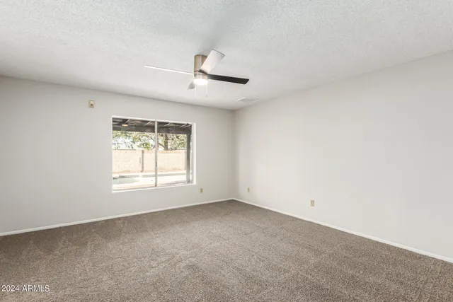 an empty room with a window and ceiling fan