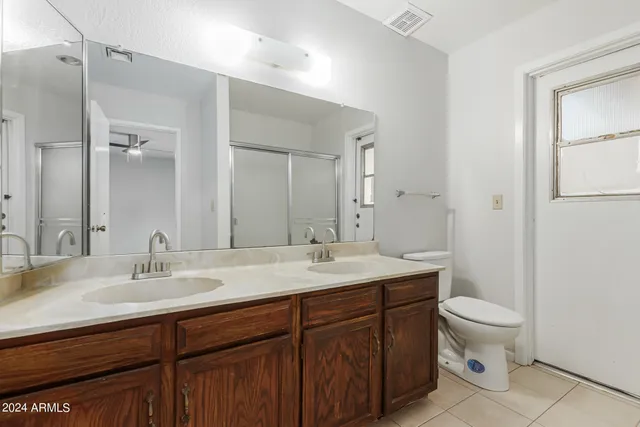 a bathroom with a sink a toilet a large mirror and shower