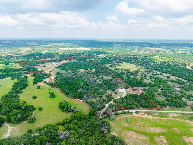 an aerial view of residential houses with outdoor space and trees