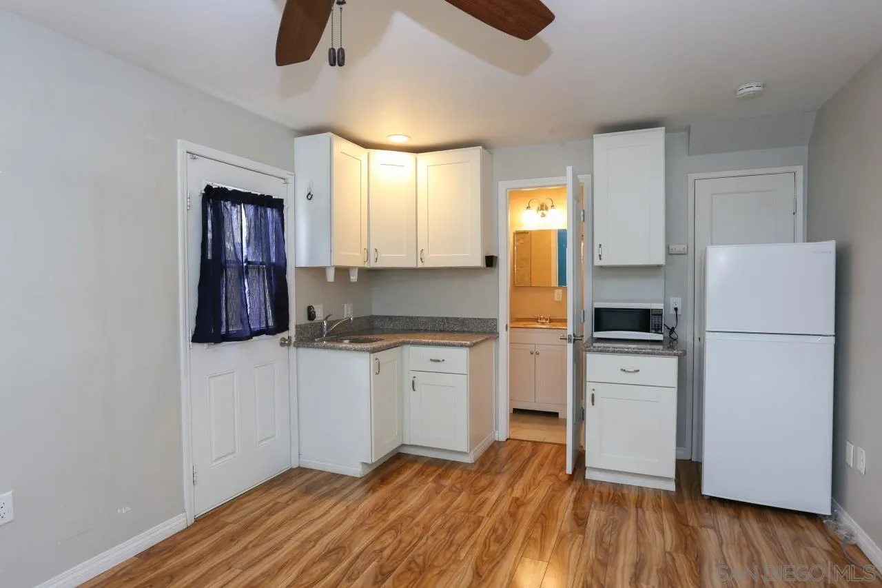 1229 Rees Road Escondido, CA 92026 - Photo 25 of 44 a kitchen with white cabinets and wooden floor