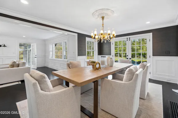 a view of a dining room with furniture a chandelier and large windows