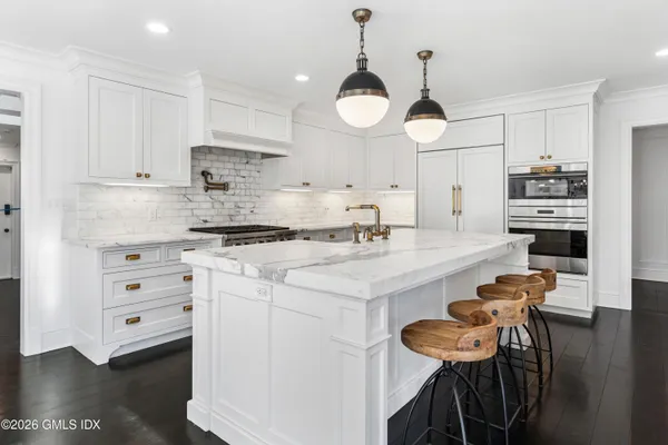 a kitchen with stainless steel appliances a stove a sink dishwasher and white cabinets with wooden floor