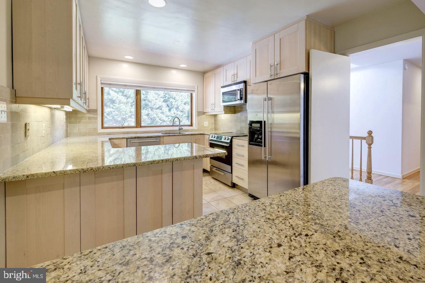 6710 Persimmon Tree Road Bethesda, MD 20817 - Photo 8 of 39 a kitchen with stainless steel appliances kitchen island granite countertop a refrigerator and a sink