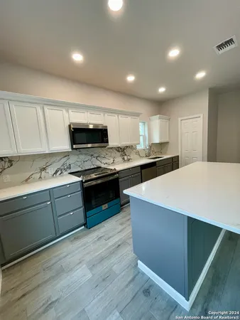 a kitchen with stainless steel appliances kitchen island granite countertop a stove a sink and a microwave