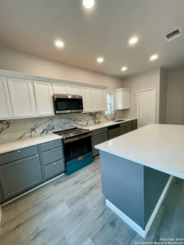 a kitchen with stainless steel appliances kitchen island granite countertop a stove a sink and a microwave