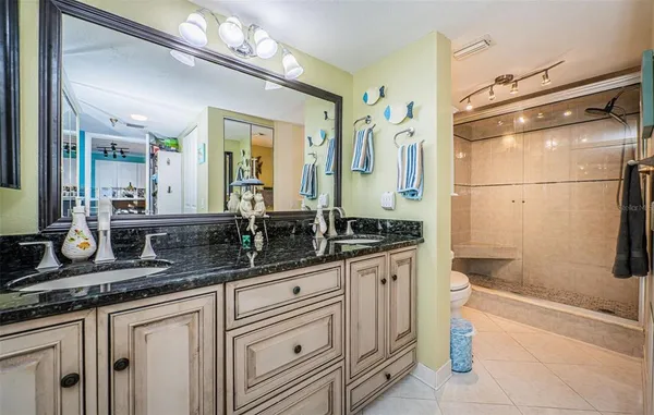 a bathroom with a granite countertop sink a toilet a mirror and shower