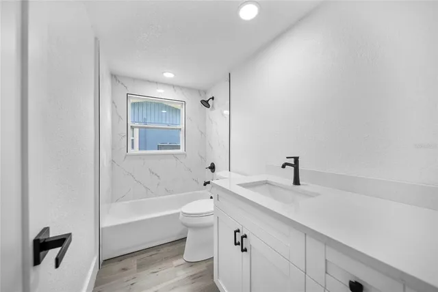 a bathroom with a granite countertop sink a toilet and bathtub