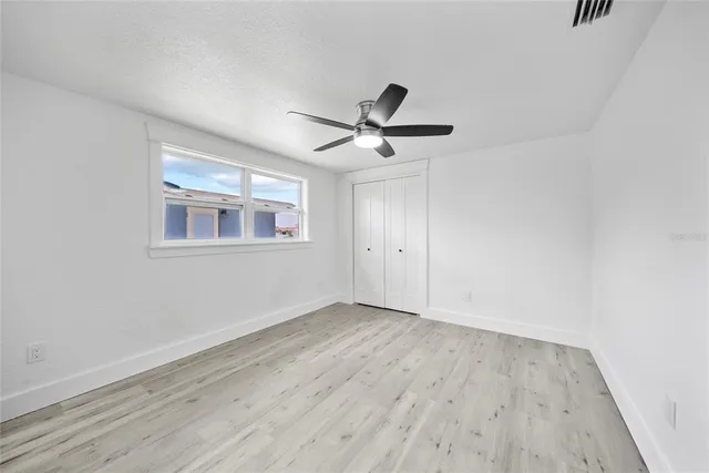 an empty room with wooden floor and ceiling fan