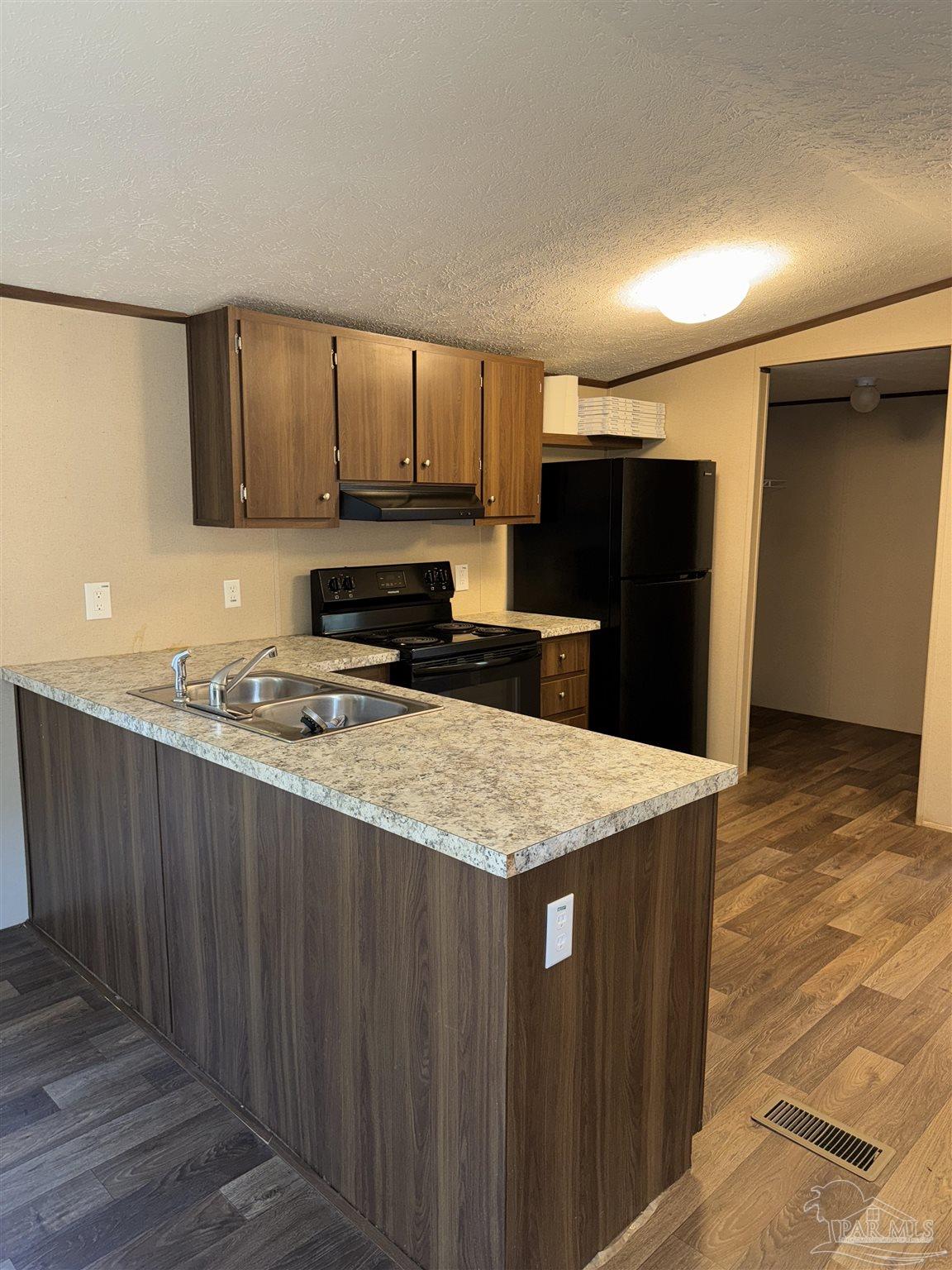 5049 Bent Tree Road Milton, FL 32583 - Photo 14 of 34 a kitchen with stainless steel appliances kitchen island granite countertop a refrigerator a stove and a sink with wooden cabinets
