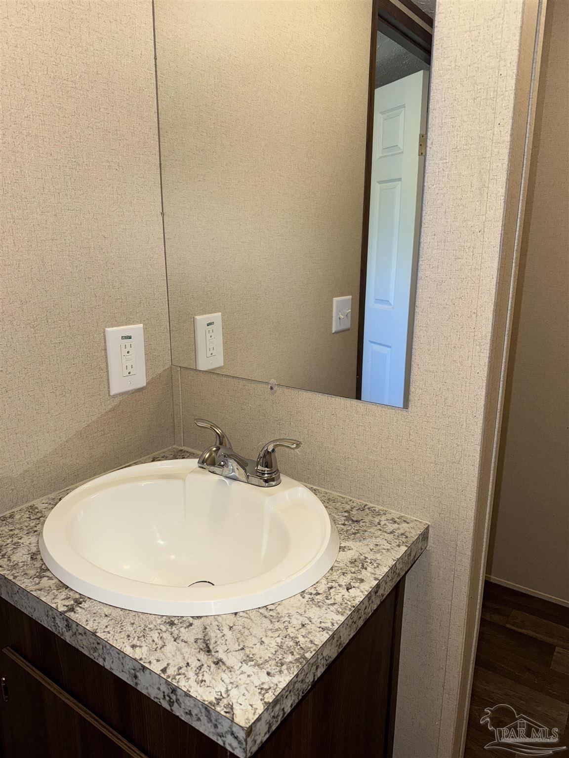 5049 Bent Tree Road Milton, FL 32583 - Photo 30 of 34 a bathroom with a granite countertop sink and a mirror