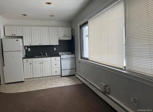 a kitchen with white cabinets and window