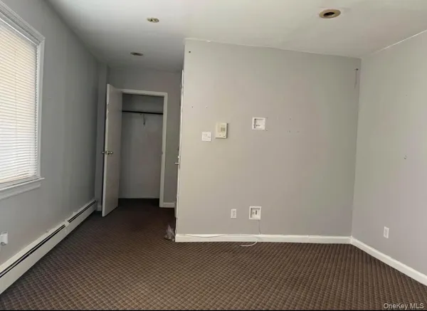 a view of an empty room with closet and a window