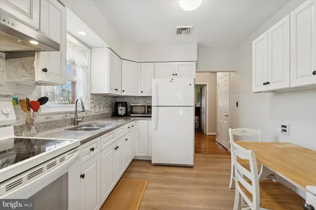 a kitchen with stainless steel appliances granite countertop a refrigerator sink and white cabinets