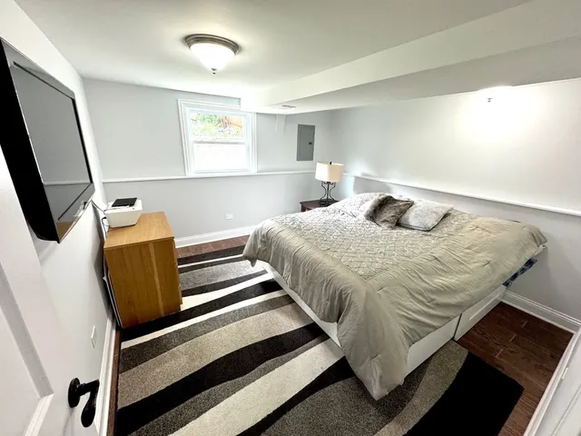 a bedroom with a bed and a flat tv screen on a dresser