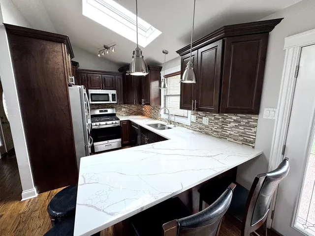 a kitchen with stainless steel appliances kitchen island a table chairs and refrigerator