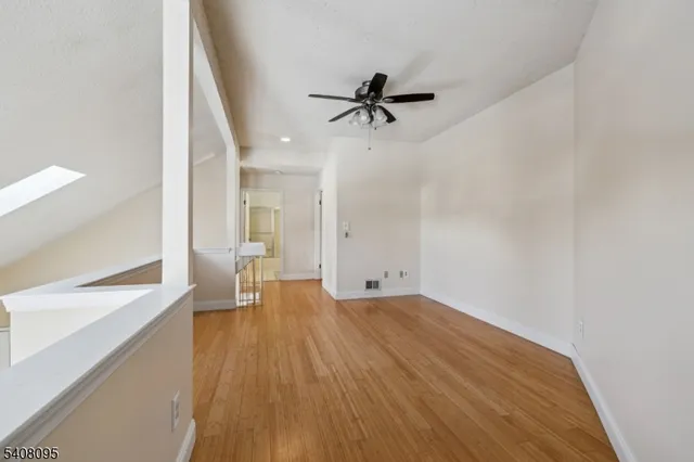 a view of a room with wooden floor and a ceiling fan