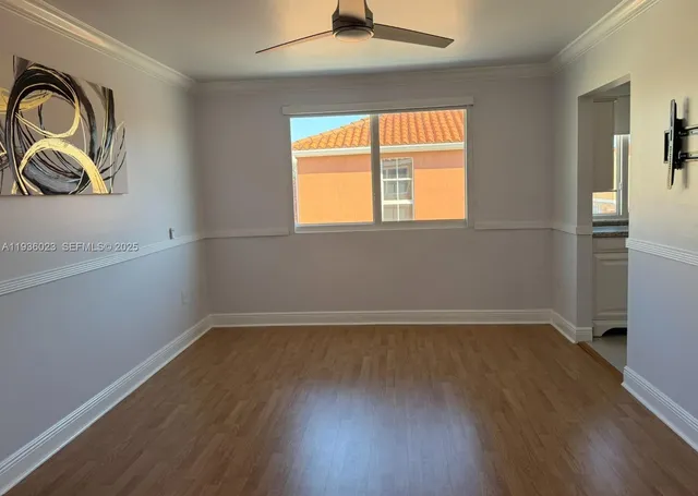an empty room with wooden floor closet and windows