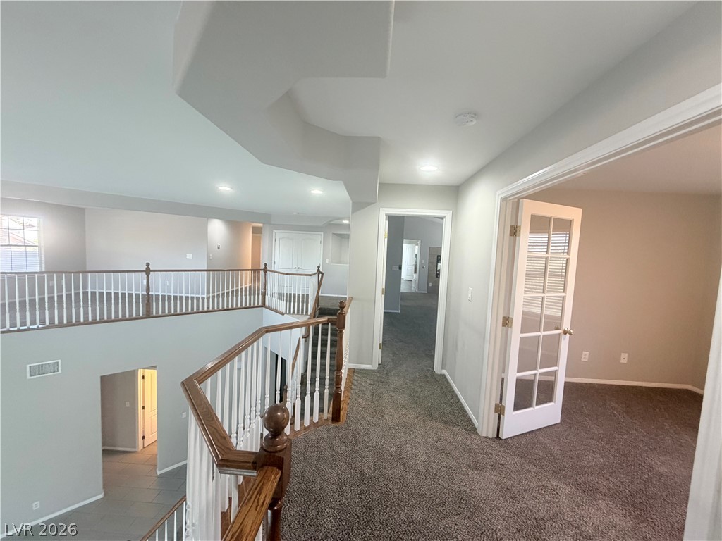 6116 Rabbit Track Street Las Vegas, NV 89130 - Photo 7 of 28 A spacious upper-level landing offers an open view of the floor below, with a private room accessible through elegant French doors.