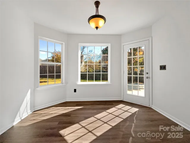 a view of an empty room with wooden floor and windows