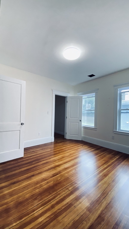 96 Brayton Road, Unit 1 Boston, MA 02135 - Photo 4 of 10 an empty room with wooden floor and windows