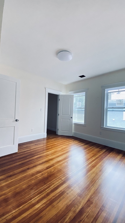 96 Brayton Road, Unit 1 Boston, MA 02135 - Photo 5 of 10 a view of an empty room with wooden floor and a window
