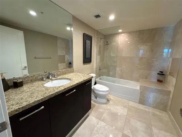a bathroom with a granite countertop sink a toilet and bathtub