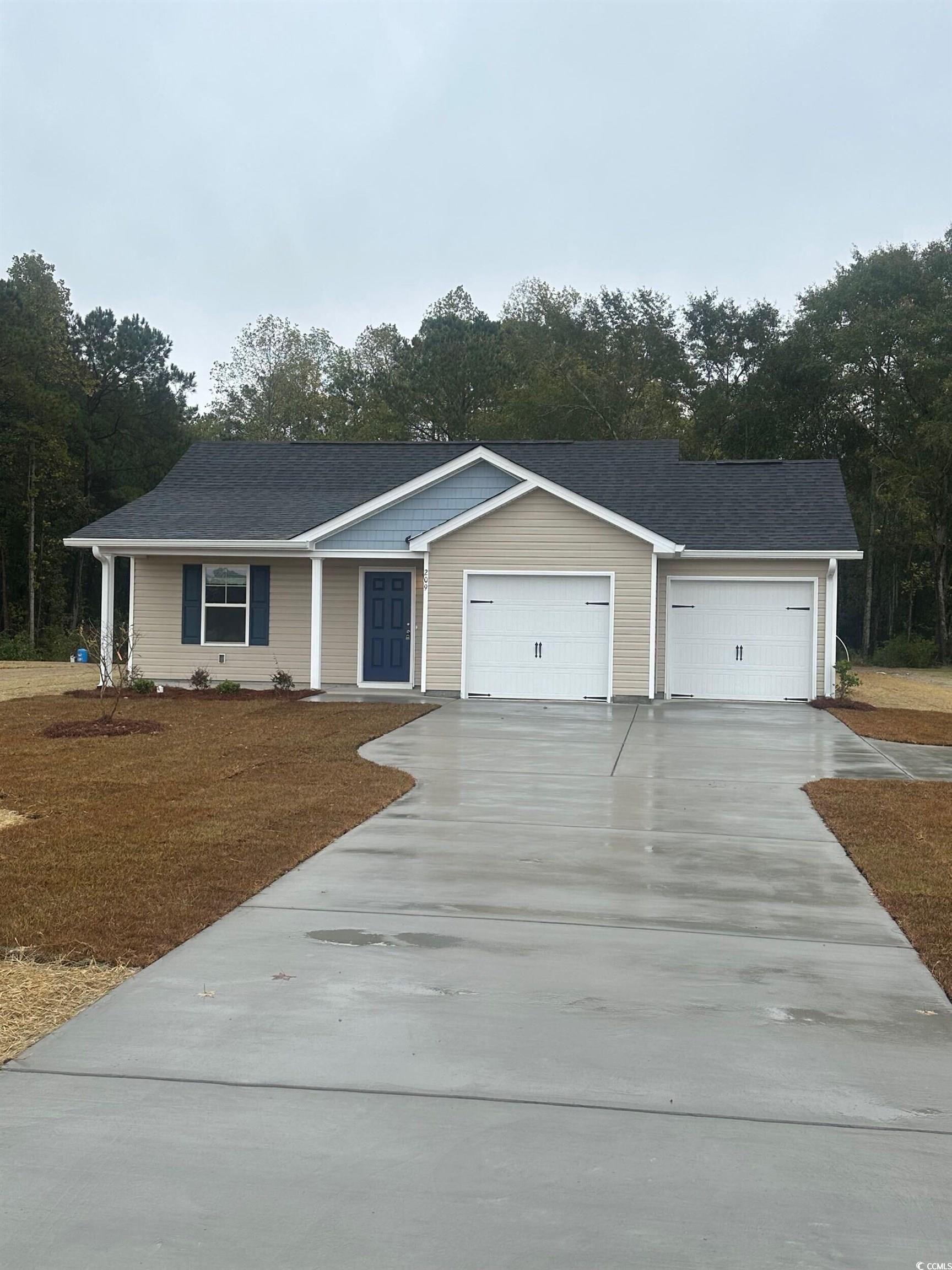 Single story home with concrete driveway, an attached garage, and view of wooded area