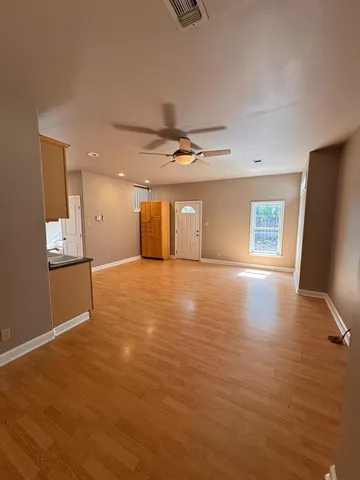 a view of an empty room with wooden floor and a window