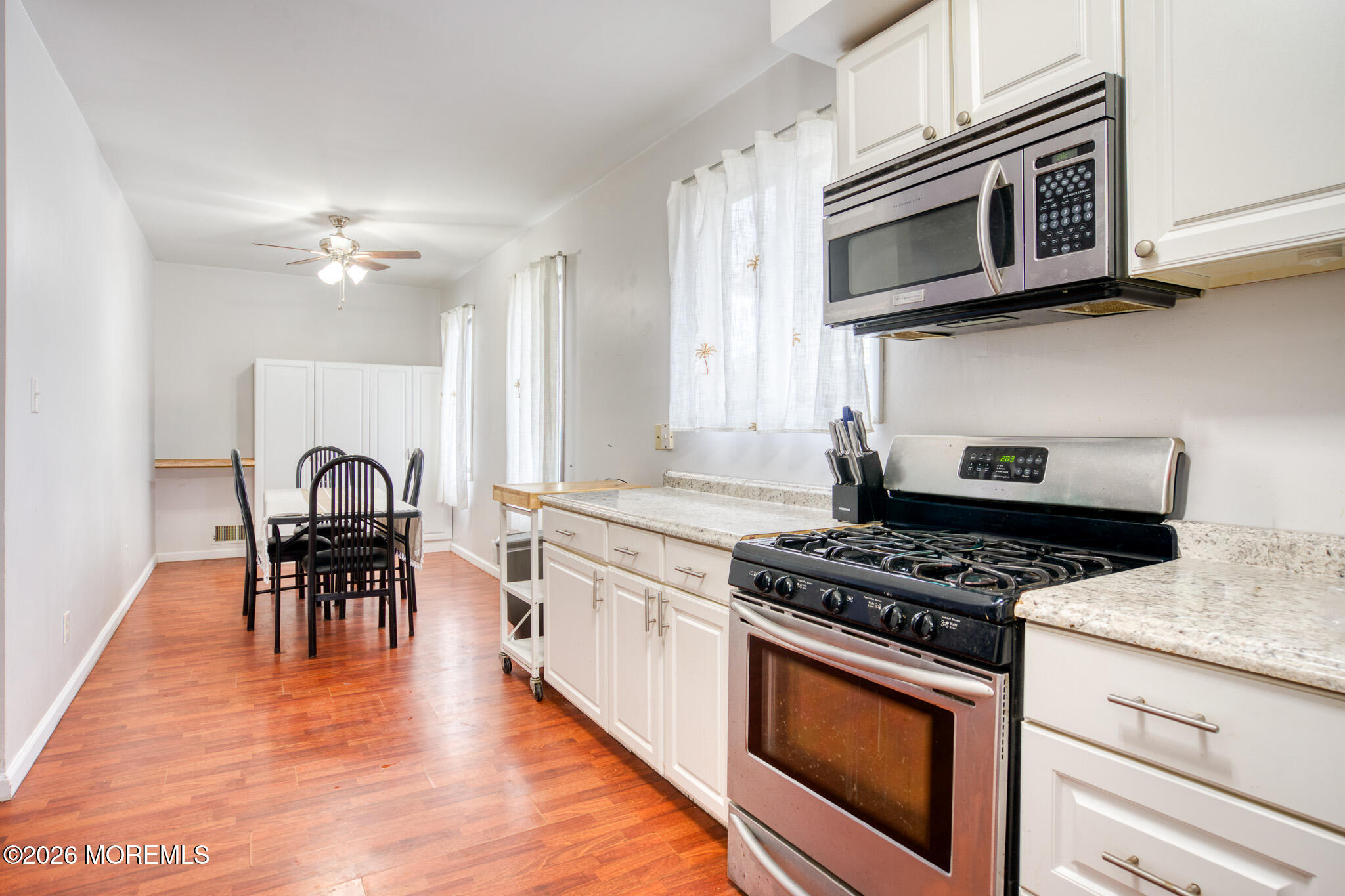 138 3rd Street Keyport, NJ 07735 - Photo 7 of 20 a kitchen with stainless steel appliances granite countertop a stove top oven a sink a dining table and chairs with wooden floor