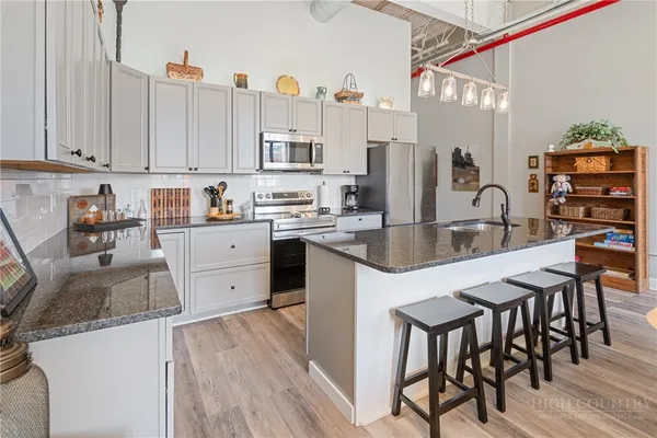 a kitchen with stainless steel appliances granite countertop a sink a stove and refrigerator