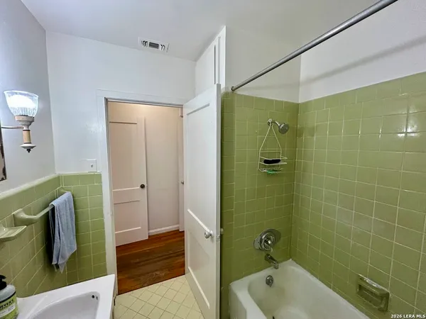 a bathroom with a tub shower and sink