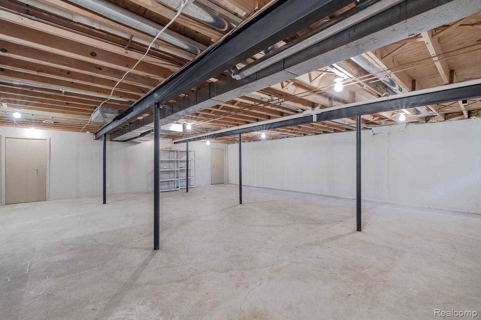 312 Reid Road Highland, MI 48357 - Photo 36 of 47 Unfinished basement with concrete flooring, exposed wood joists, structural steel beams, white painted walls, and overhead lighting