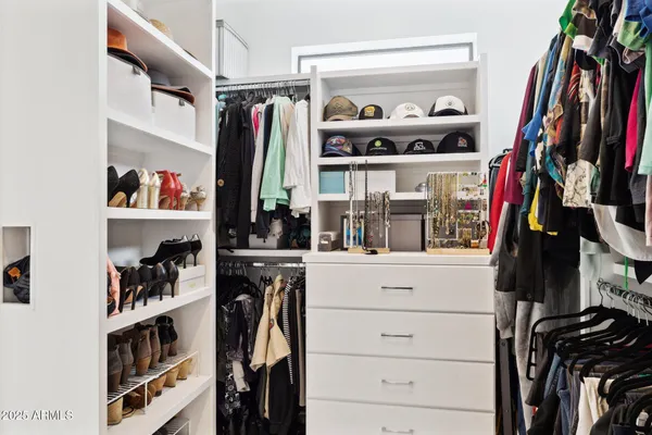 a view of walk in closet with clothes and shoes