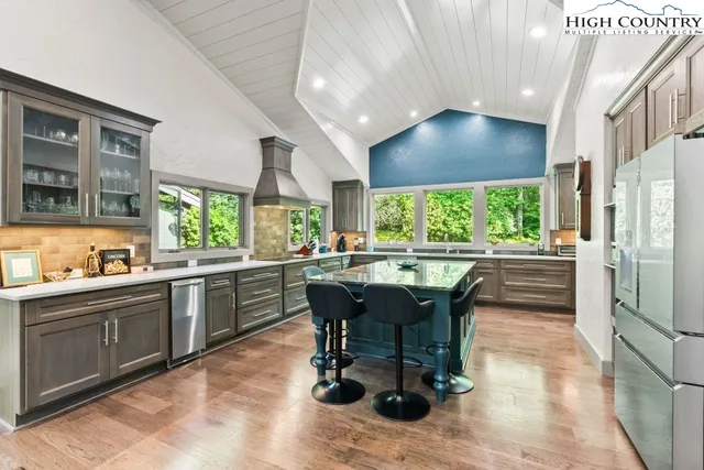 a kitchen with stainless steel appliances granite countertop a table chairs and a refrigerator