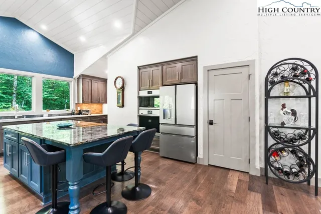 a view of a dining room with furniture one side kitchen view and wooden floor