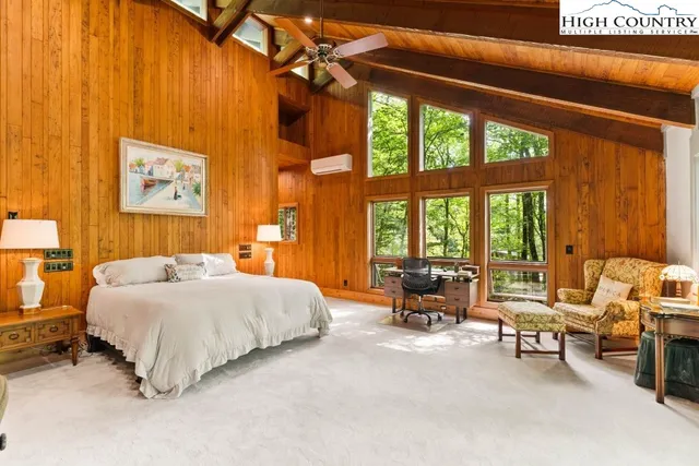 a bedroom with a bed and large windows