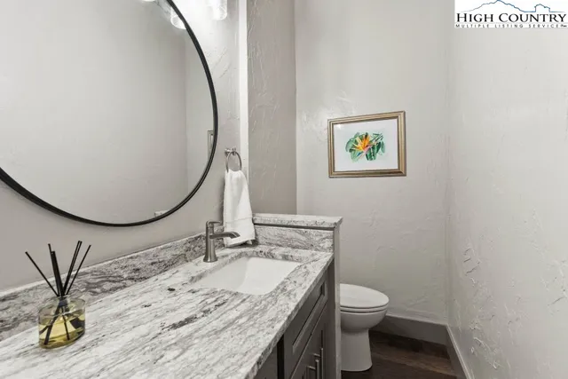 a bathroom with a granite countertop sink a toilet and a mirror