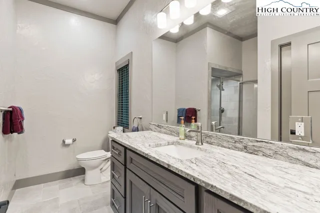 a bathroom with a granite countertop sink a toilet and a mirror