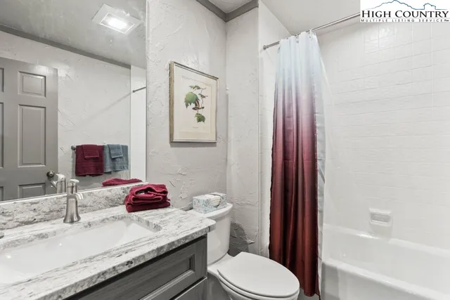 a bathroom with a granite countertop sink toilet and shower