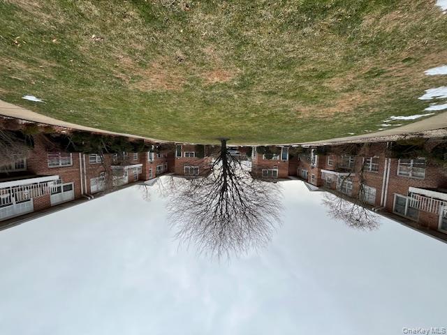 84 Shore Road, Unit D2 Port Washington, NY 11050 - Photo 2 of 12 a tall house with a yard and a large tree